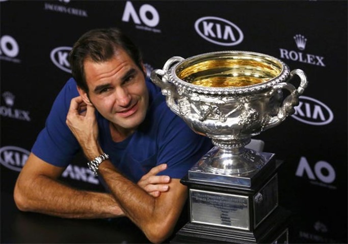 Roger Federer, seen with the trophy, reacts during a post-match news conference