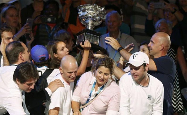 Members of Federer’s coaching box are seen with the championship trophy