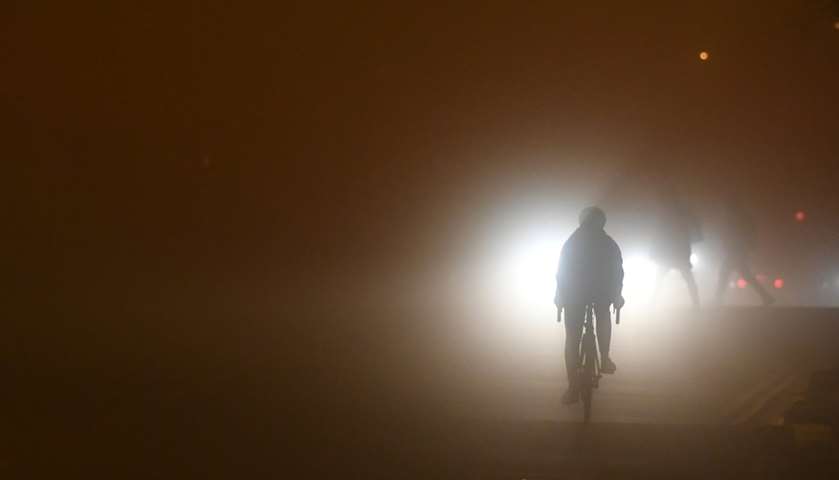 A person cycles through heavy fog in Dublin, Ireland