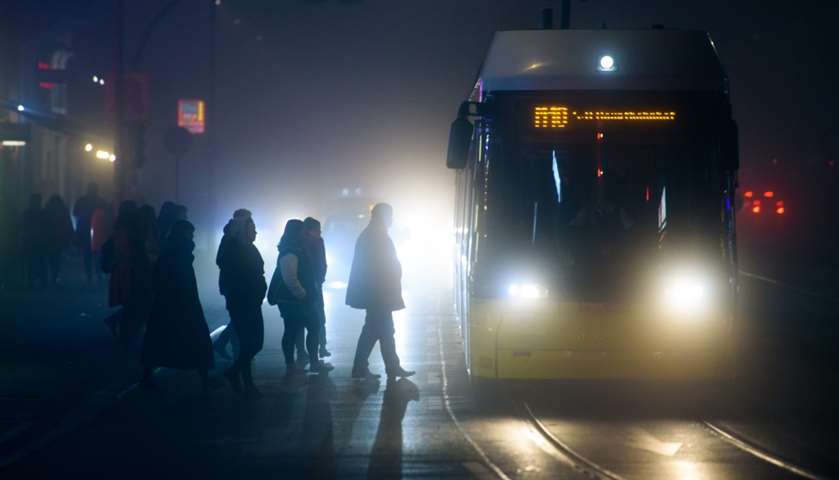 Commuters silhouette against the backlight of car headlights- Berlin, Germany