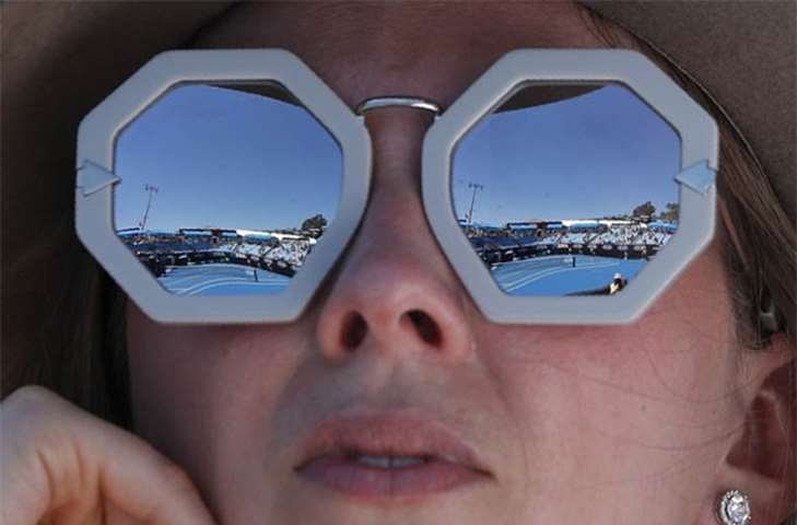 The court is reflected in the sunglasses of a spectator as she watches a game at the Australian Open