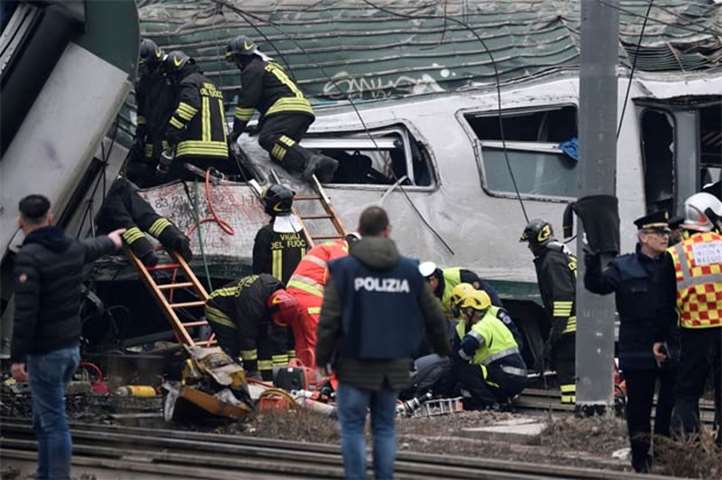Firefighters and police officers work around derailed trains in Pioltello, on the outskirts of Milan
