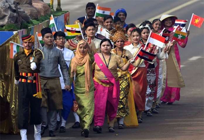 Indian volunteers walk alongside a tableau holding the national flags of the Asean countries