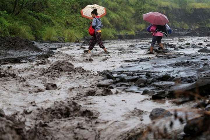 Residents wade through a river mixed with lahar from Mount Mayon volcano in Daraga