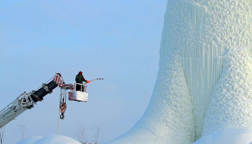 A worker on a crane prepares a 30-metre tall ice tower ahead of the Harbin International Ice and Sno