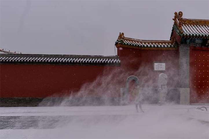 A Chinese tourist stands by the Imperial Palace during a snowfall in Shenyang