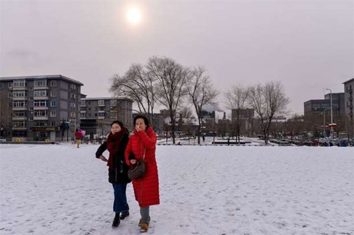 Chinese women walk in snow at Shenyang\'s Imperial Palace