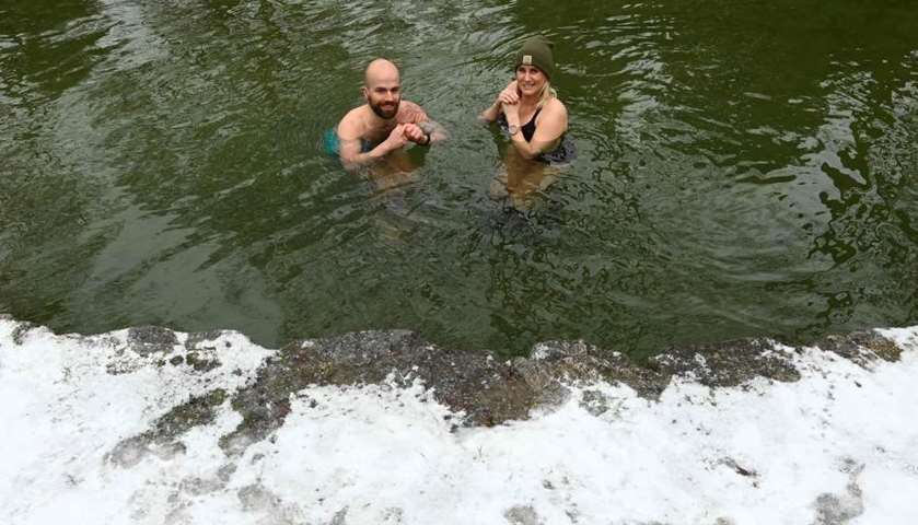 The ice swimmer Erina Hey and Franz Mayr pose in the canal of Eisbach river at the English Garden pa
