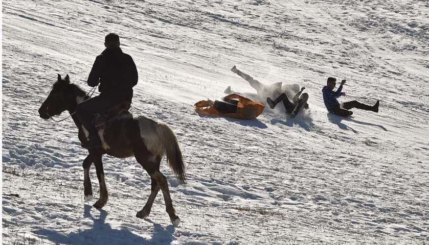 People on a snow tube slide down a hill near the village of Arashan, Bishkek