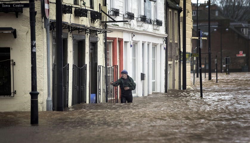 A man wades in floodwaters in a street in Dumfries.