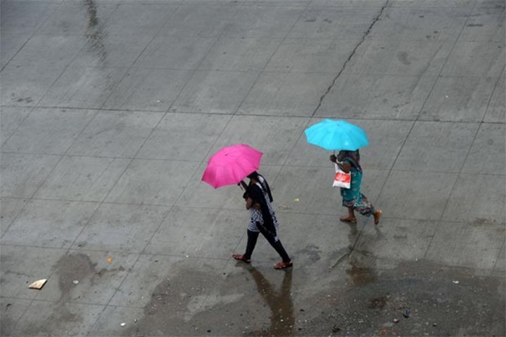 Women walk with umbrellas in a residential area during heavy rains in Chennai on Thursday