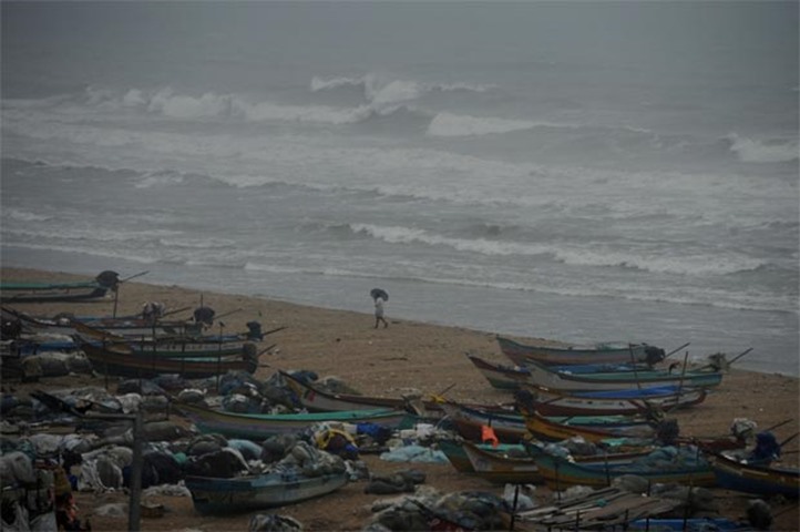 An Indian fisherman walks near boats in Chennai as a cyclone is expected to make landfall