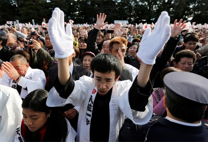 People raise their hands as they shout \'banzai\', or cheer, in Tokyo on Friday