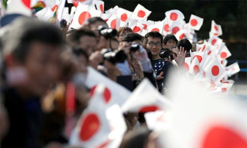 Well-wishers wave Japanese national flags outside the Imperial Palace in Tokyo on Friday