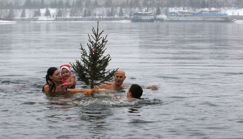 A winter swimmers club members swim with a Christmas tree in Yenisei River in Krasnoyarsk, Russia
