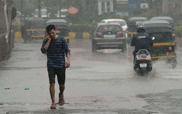 A man speaks on a phone as he walks through a flooded street in Mumbai