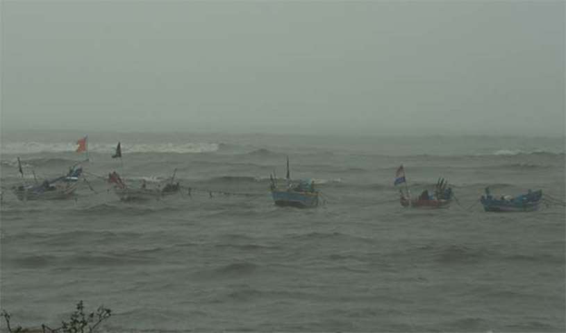 Anchored fishing boats are seen bobbing in the rough sea off a beachfront promenade in Mumbai