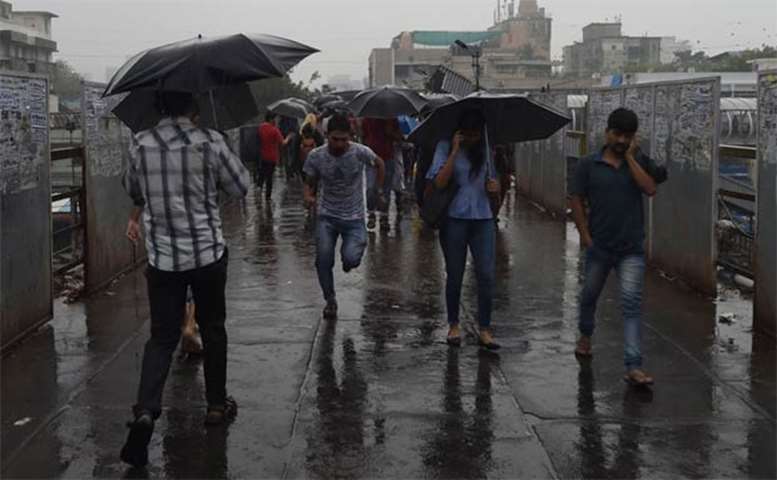 Indian commuters protect themselves during rain from Cyclone Ockhi in Mumbai