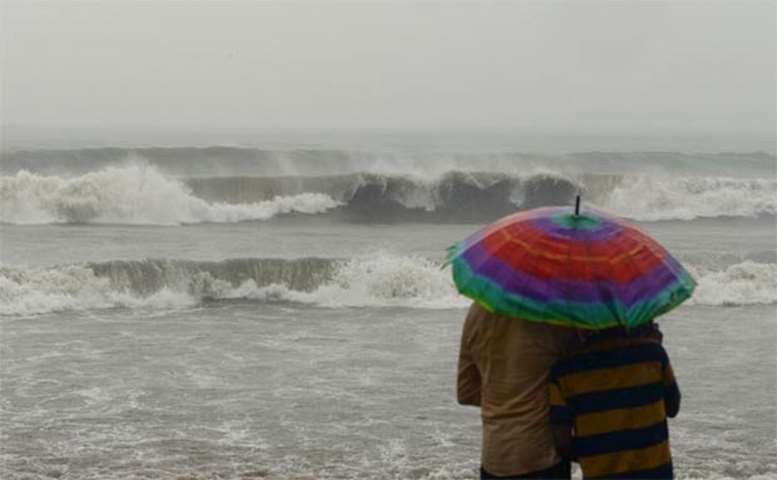 People watch rough sea waves at Juhu beach in Mumbai