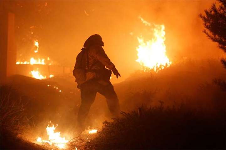 A firefighter stomps out small embers on a ranch during the Creek Fire in the San Fernando Valley