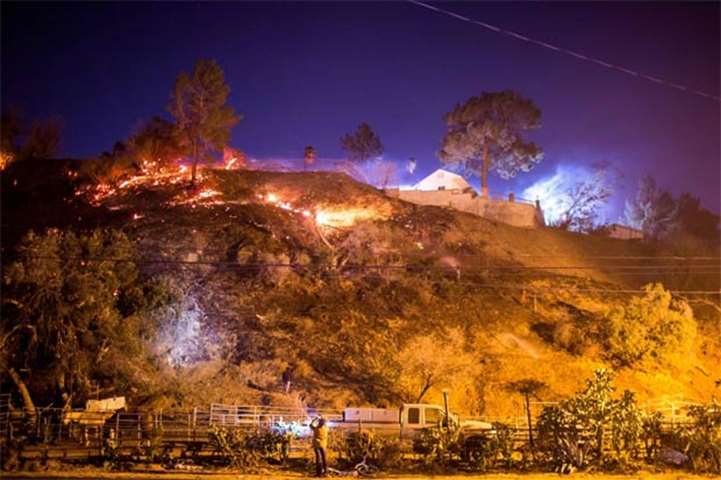 The Creek Fire burns behind a hillside near houses in the Shadow Hills neighbourhood of Los Angeles