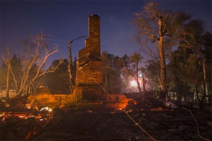 Strong wind blows embers across the smouldering ruins of a house at the Creek Fire in Sunland