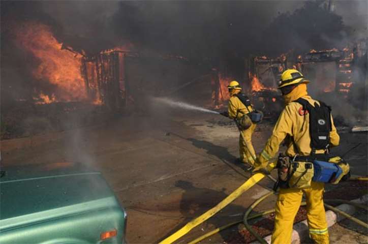 Firefighters try to save a house during the Thomas wildfire in Ventura, California on Tuesday
