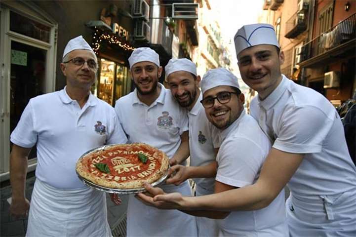 Neapolitan pizza makers pose with a pizza celebrating the Unesco decision, in Naples on Thursday
