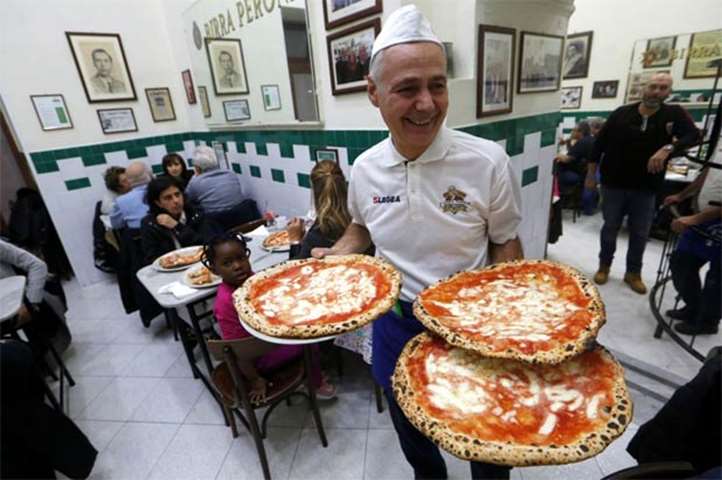A waiter serves Pizza Margherita at L\'Antica Pizzeria da Michele in Naples