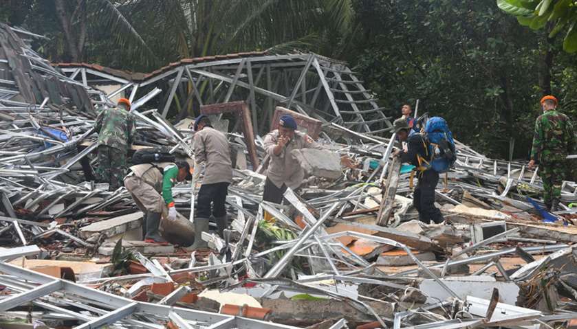 Indonesian policemen and soldiers search through rubble for victims in Carita, Banten province