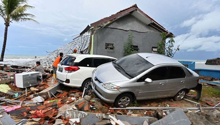Two damaged cars are seen as members of an Indonesian search and rescue team look for victims