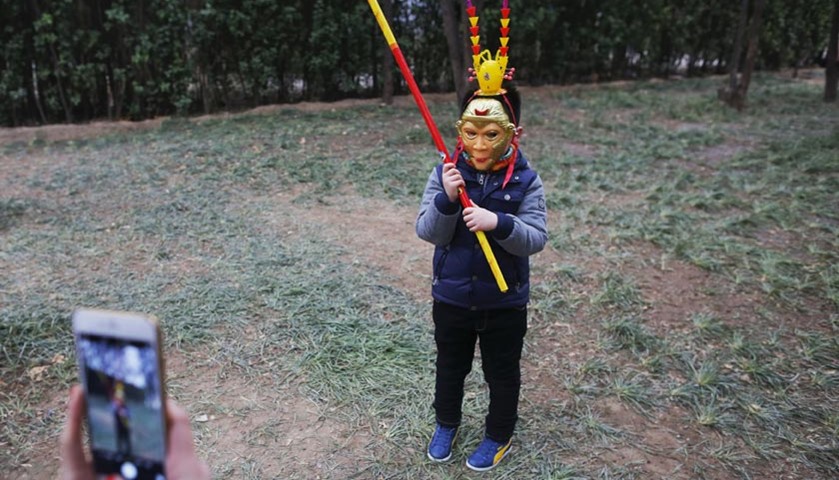 A boy wearing a mask poses for pictures at Ditan Park (the Temple of Earth), in Beijing