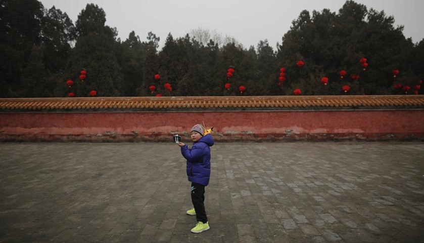 A boy strikes a pose while taking pictures of himself at the temple fair at Ditan Park in Beijing