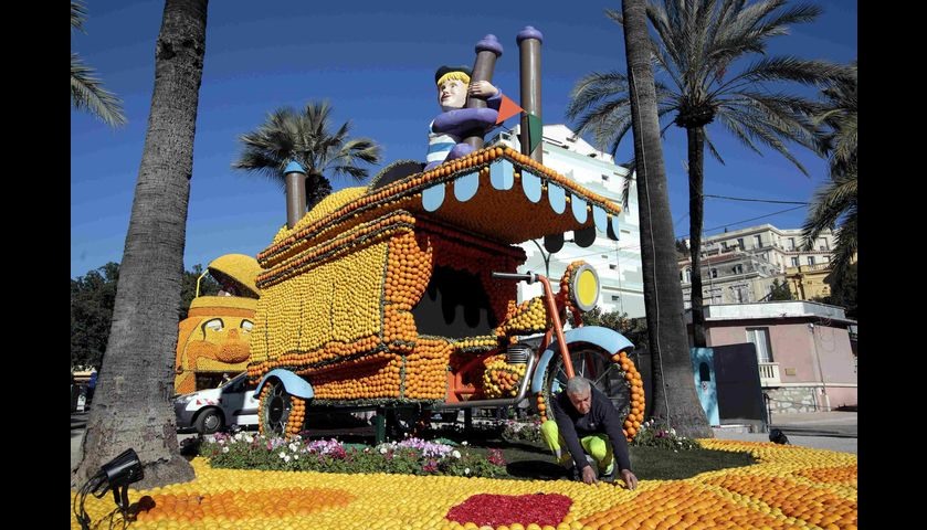 A worker puts the final touch to a replica of a giant triporter made with lemons and oranges which s