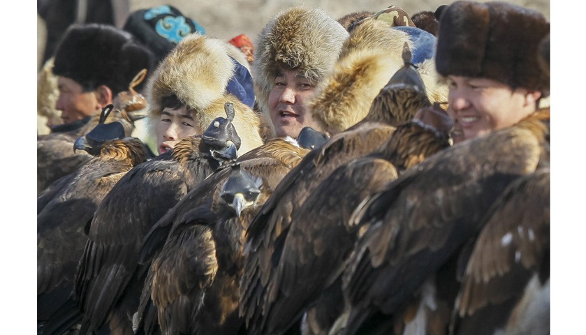 Hunters hold their tamed golden eagles at a parade during the traditional hunting contest outside th