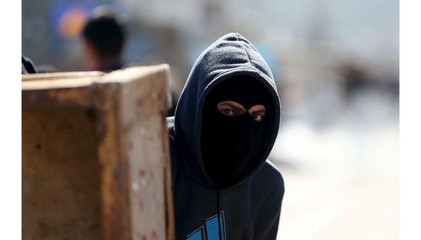 A Palestinian protester takes cover during clashes with Israeli troops