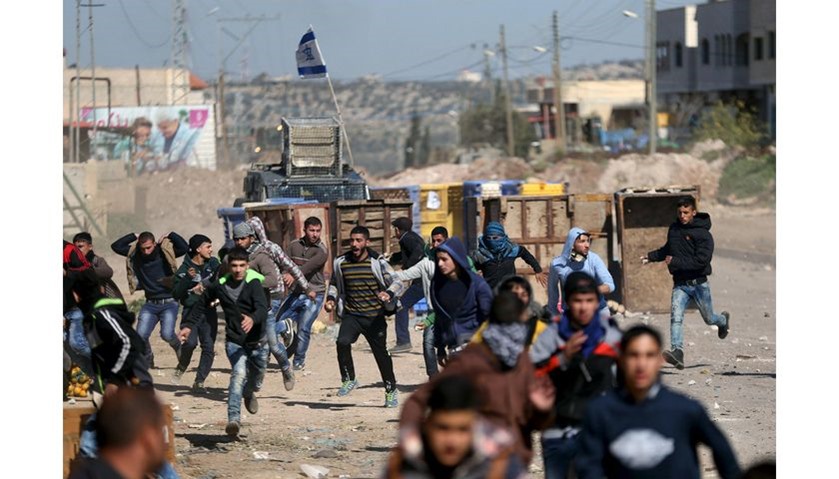 Palestinians run for cover during clashes with Israeli troops in the West Bank village of Qabatya