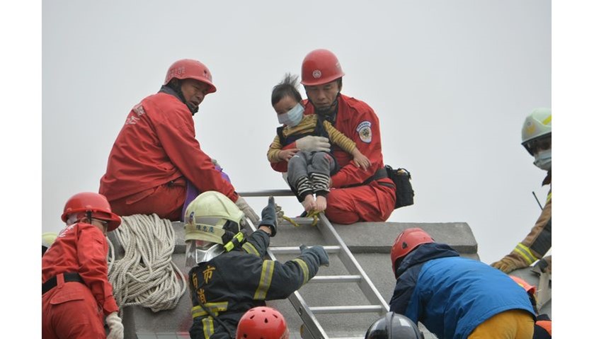 Rescue personnel help a young victim at the site of a collapsed building in the southern Taiwanese c