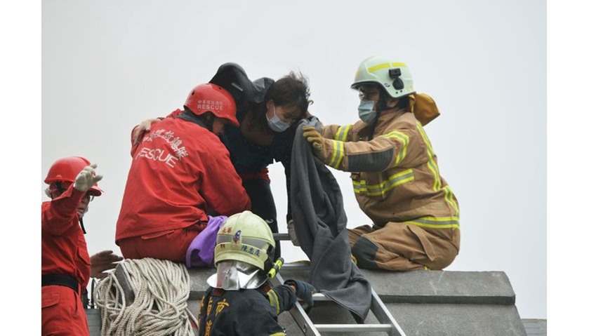 Rescue personnel help a victim at the site of a collapsed building in the southern Taiwanese city of