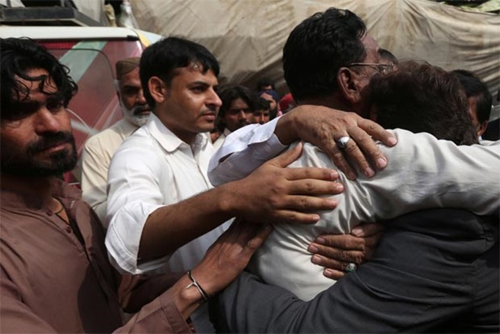 Men comfort each other as they attend the funeral of a relative on Friday