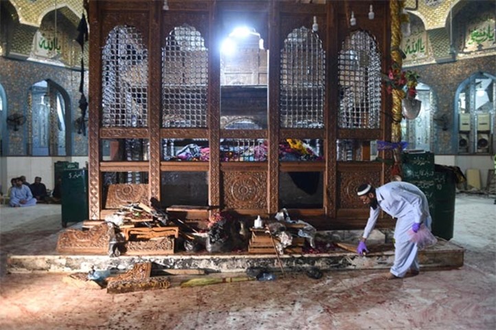 A Pakistani security official collects evidence a day after the suicide blast at the shrine