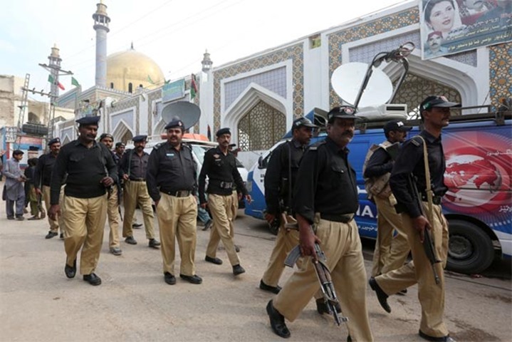 Policemen gather outside the tomb of Sufi saint Syed Usman Marwandi in Sehwan Sharif on Friday