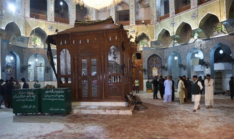 Pakistani security officials inspect the blood-stained floor after a bomb attack hit the Sufi shrine