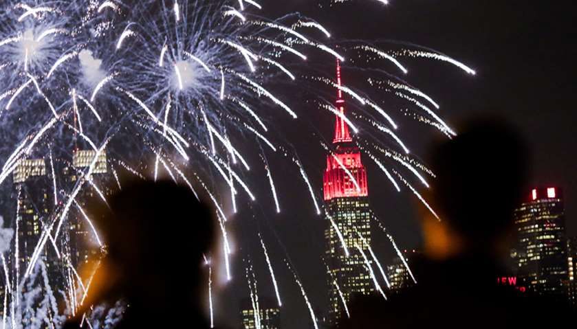 People watch fireworks explode against the backdrop of the Empire State Building