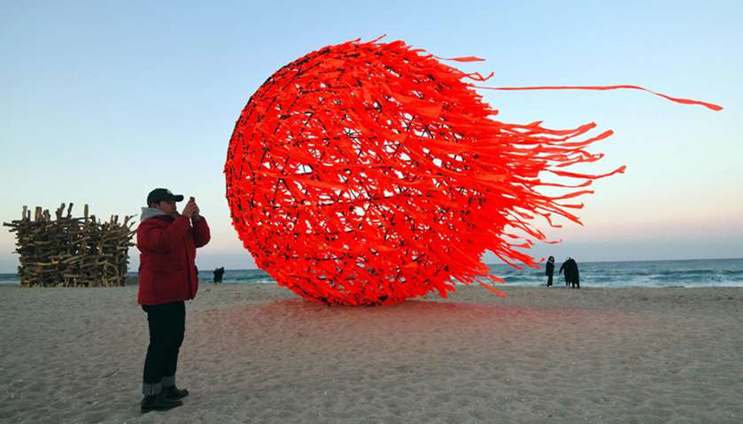 A man takes picture of an art work installation of the sun at Gyeongpo beach in Gangneung