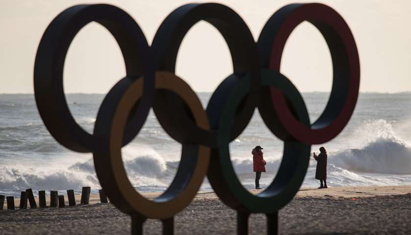 People take photos before the Olympic Rings during sunrise on Gyeongpo beach in Gangneung