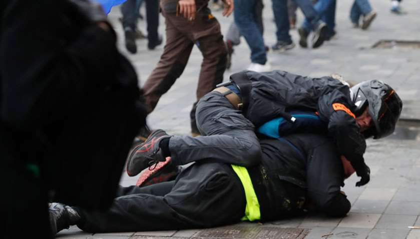 A plain clothes riot policeman (TOP) tussles with a yellow vest protestor during a march in Paris