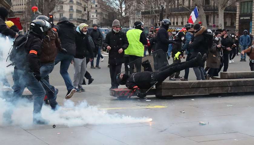 Protesters watch as a plain-clothes police officer falls over during clashes at Place de la Republiq