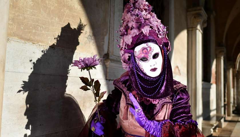 A reveller wearing a mask and a period costume takes part in the Carnival