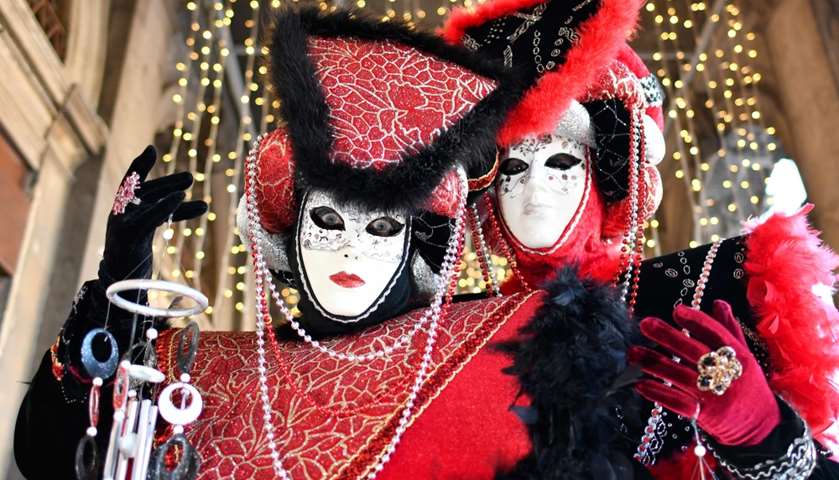 Revellers wearing a mask and a period costume take part in the Carnival
